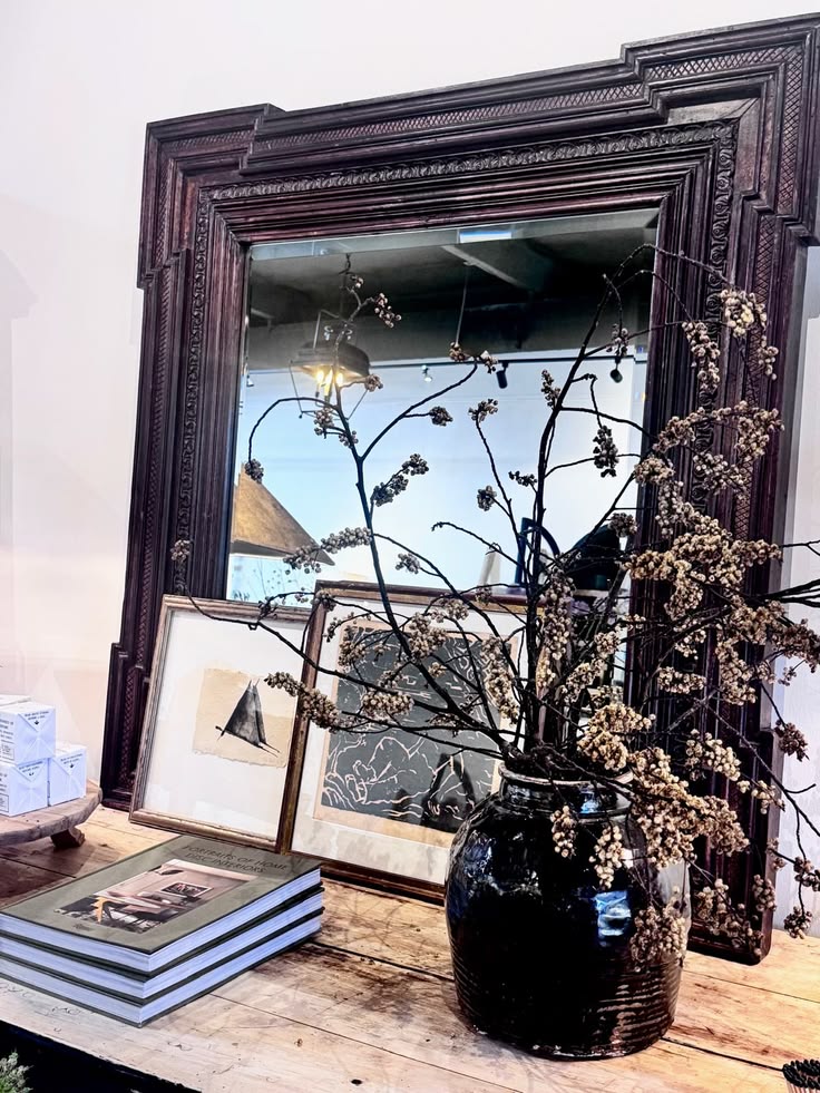 Carved mirror, books, framed art, and dried branches